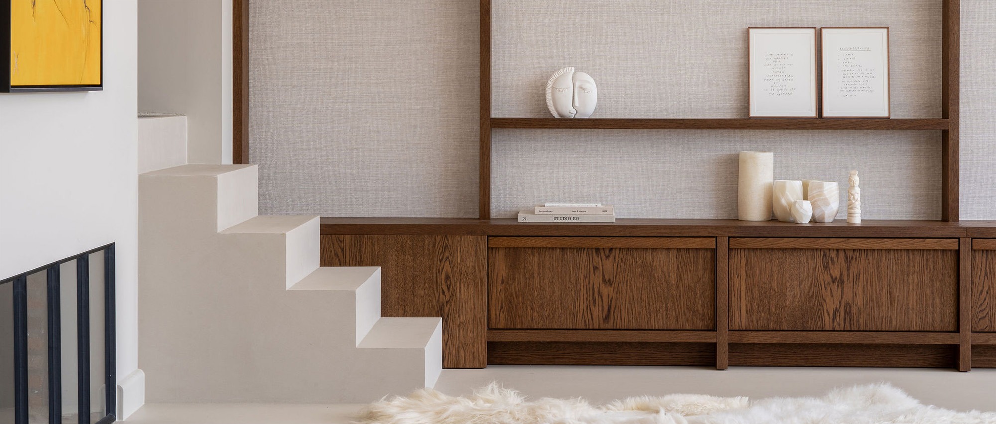 Interieur van een nieuwbouwwoning met witte maatwerktrap en houten wandkast